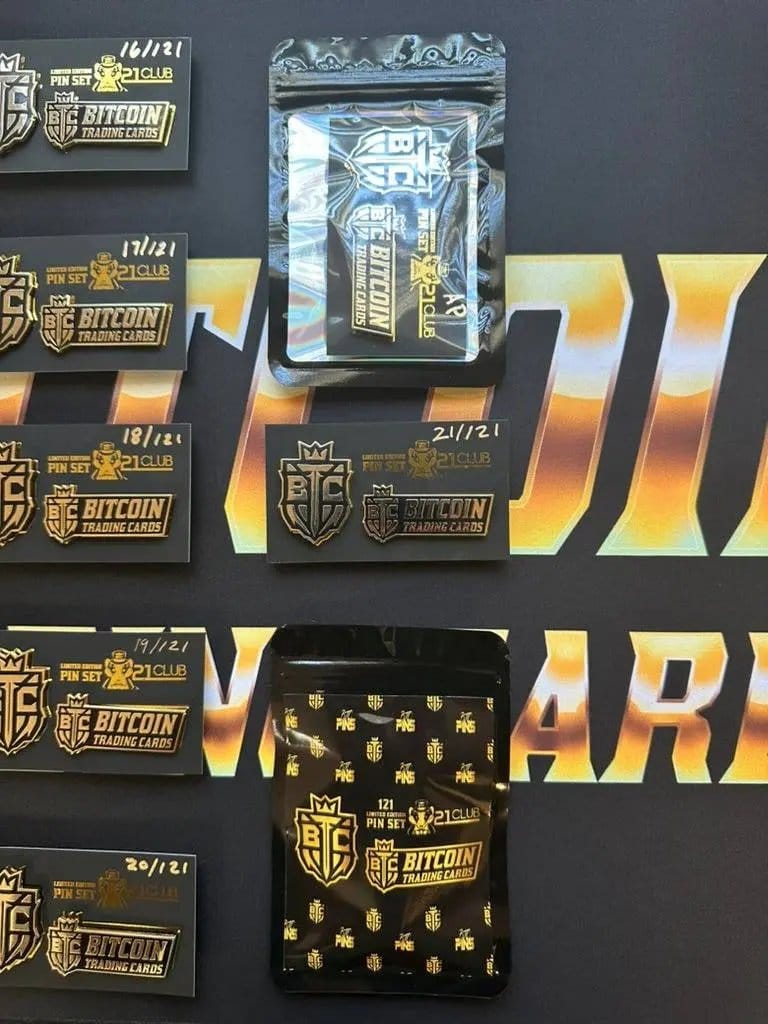 Close-up photograph of the right side of the '21 Club' pin set grid, clearly showing numbered sets 16/121 through 21/121, along with a packaged set in a holographic bag and a reverse-side packaged set.