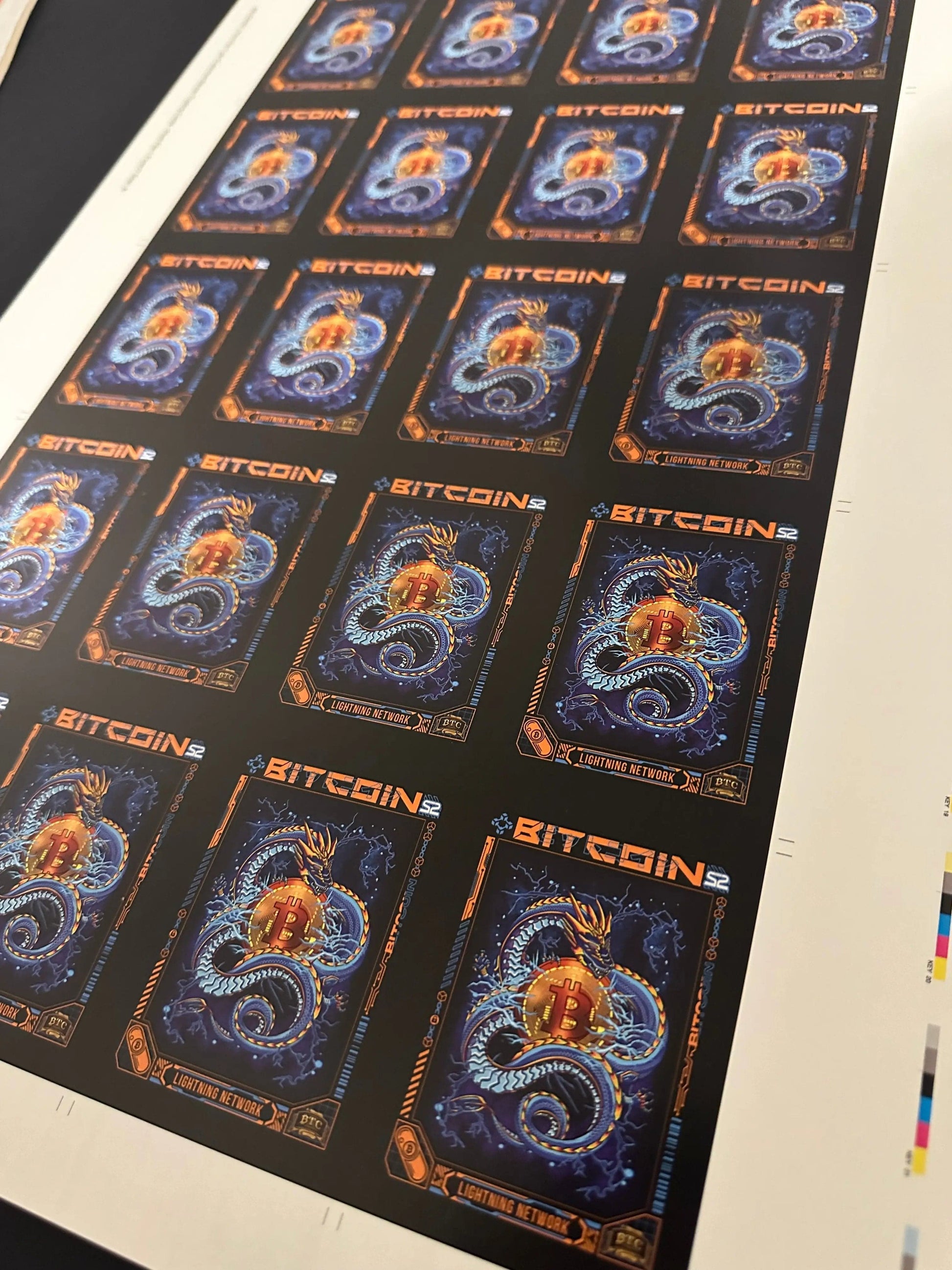 Angled perspective view of an uncut production press sheet for Bitcoin Trading Cards featuring a grid of the 'Lightning Network' blue dragon card artwork. 