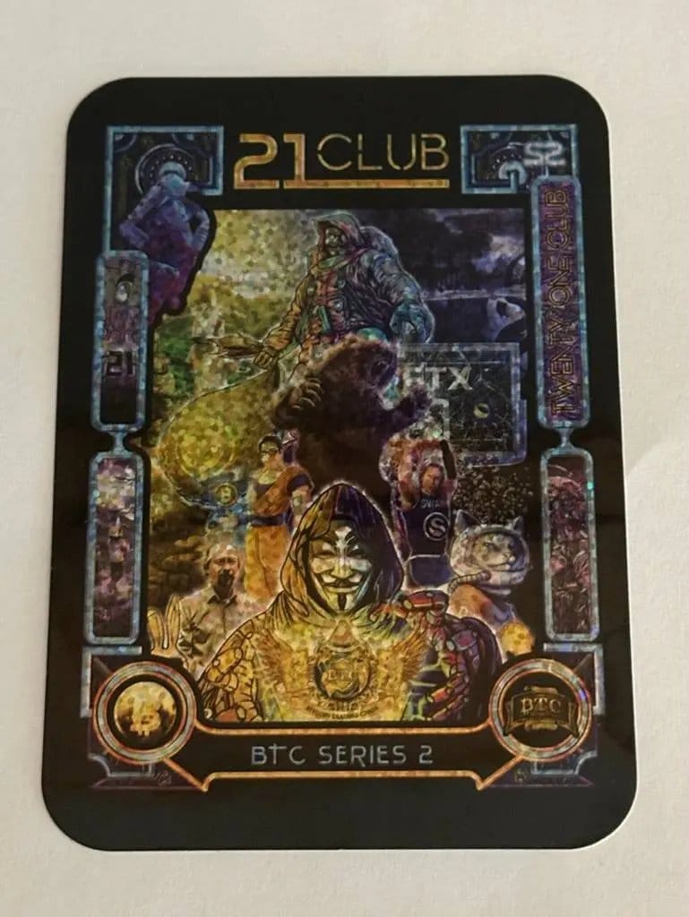 Close-up photograph of the limited edition '21 Club' Series 2 holographic sticker, featuring a pixelated collage of characters including the FUD bear, Guy Fawkes mask figure, space cat, and FTX tombstone.