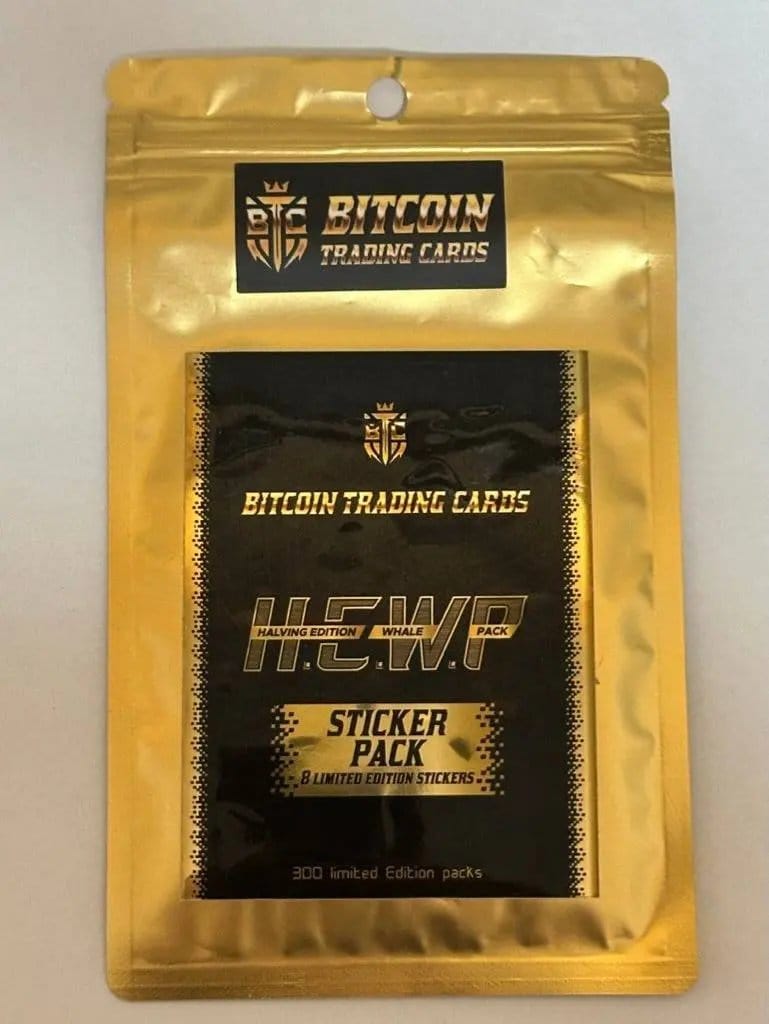 Physical photograph of the gold foil 'H.E.W.P' (Halving Edition Whale Pack) Sticker Pack for Bitcoin Trading Cards, sitting on a plain white background, showing the black label with gold text stating '8 LIMITED EDITION STICKERS' and '300 limited Edition packs'.